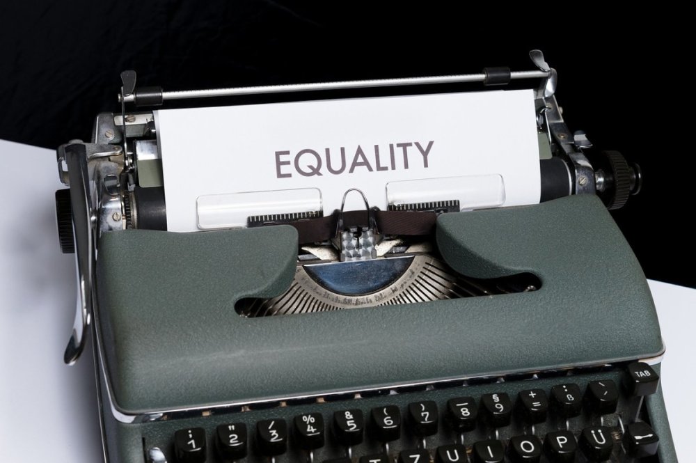 an old typewriter that has a piece of paper saying "equality".
