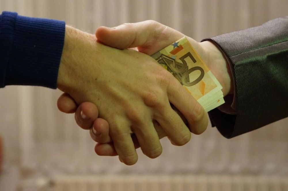 startup founders shaking hands passing money as repayment.